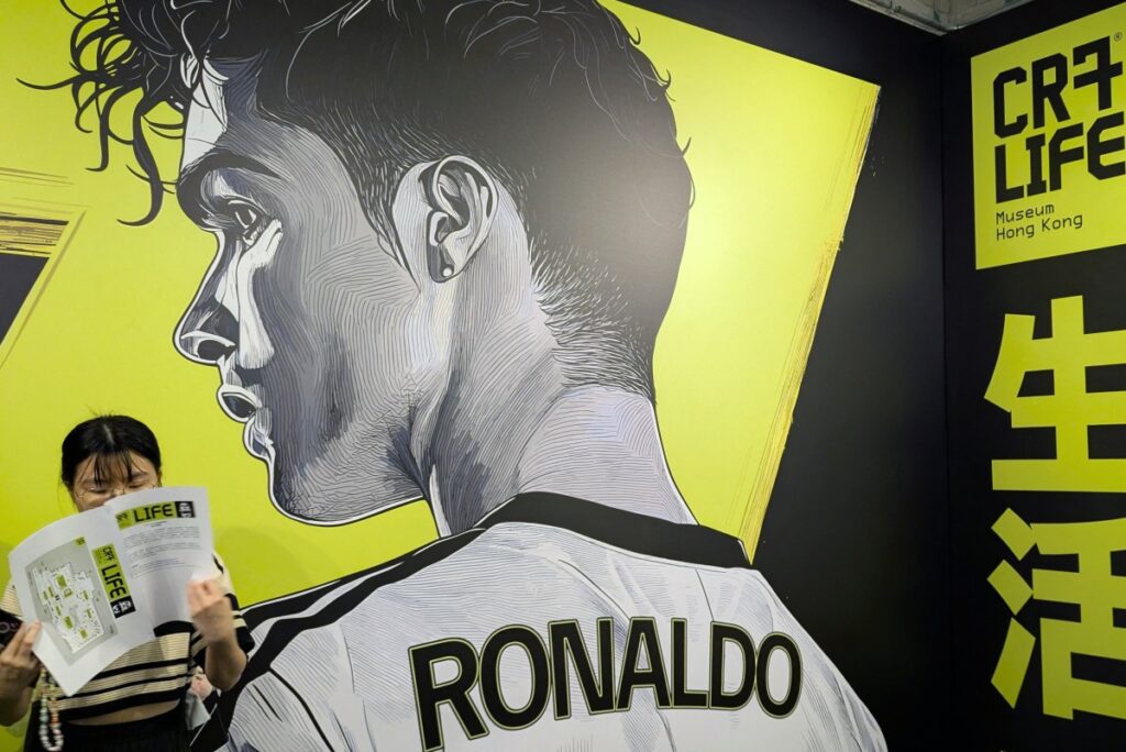 A visitor L stands in front of a large mural of footballer Cristiano Ronaldo during the opening of the CR7 LIFE Museum in Hong Kong