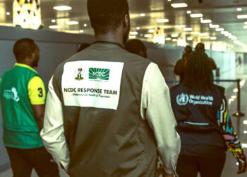 A photo of an NCDC official and two others on duty