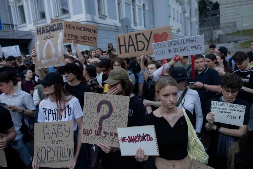 Protesters hold placards during a demonstration calling for the Ukrainian president to veto a law passed by parliament that reduces the powers of Ukraine