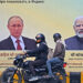 Commuters move past a hoarding with portraits of Russia’s President Vladimir Putin (L) and India’s Prime Minister Narendra Modi in New Delhi.