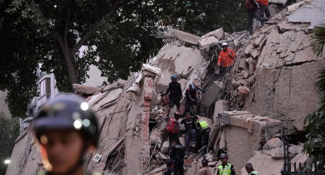 Rescue workers evacuate an injured person from a collapsed building following an earthquake in Carac